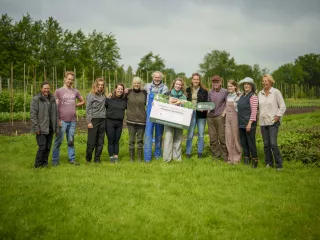 Groepsfoto van betrokkenen Sociale Voedseltuin Nieuwehorne met een cheque van 5000 euro in handen